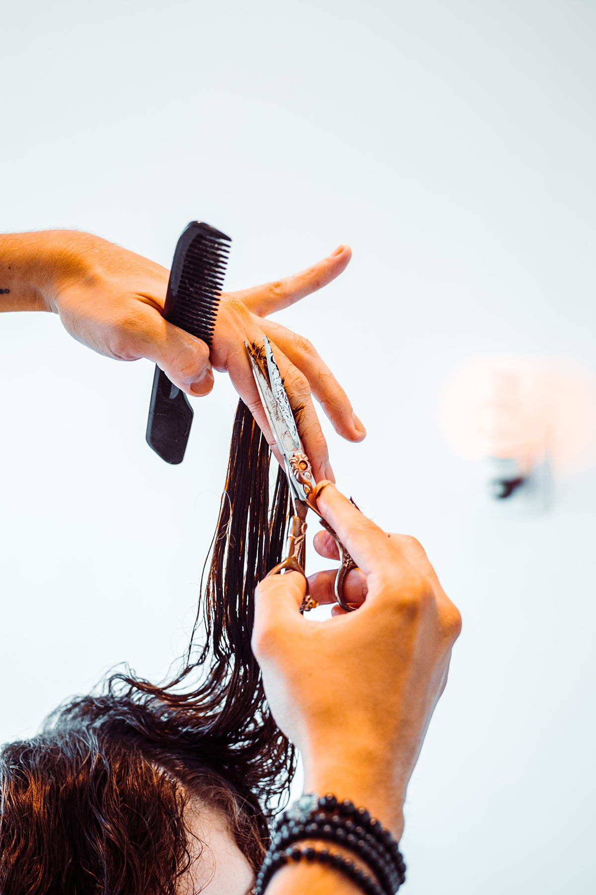 Coiffeuse coupant les pointe d'une cliente au cheveux humides